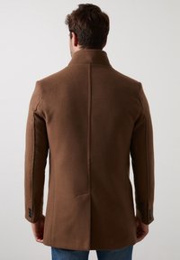 Brun ullblandad kappa med hög krage, skräddarsydd passform, rena linjer och knäppte manschetter, med en mittbakssömnad för extra struktur.