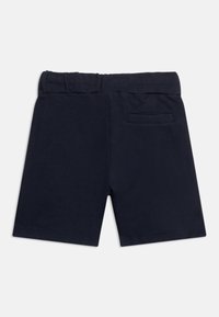 Σκούρο μπλε σορτς με ελαστική μέση και μια απλή τσέπη στο πίσω μέρος, απεικονιζόμενα από πίσω σε λευκό φόντο.