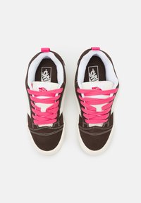 Bruna mockasin-sneakers i mocka med ljusrosa snören, vita detaljer och en vadderad krage. Har en Vans-logga på tungan och sidan.