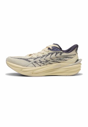 Hellbeiger Laufschuh mit gemustertem Mesh-Obermaterial, dicker strukturierter Sohle und dunklem gepolstertem Kragen, seitlich dargestellt.
