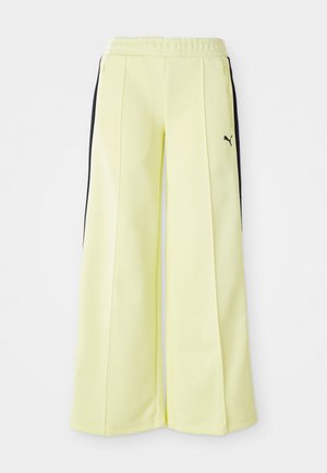 Light yellow sweatpants with black side stripes, elastic waistband, and zipper pockets. Features a Puma logo on the left side.
