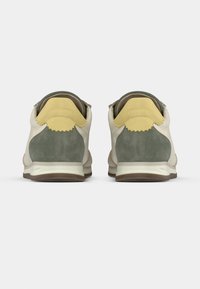 Αθλητικά παπούτσια με χρωματικό συνδυασμό σε μπεζ, πράσινο και κίτρινο. Υφάσματα από σουέντ και δέρμα, στρογγυλεμένο σχήμα και υφασμάτινες λεπτομέρειες στη φτέρνα.