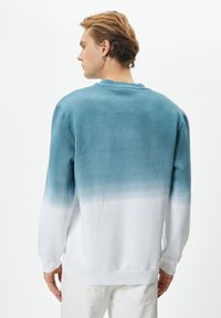 Felpa leggera in cotone con un design a gradiente; teal che sfuma verso il bianco, polsini e orlo a coste, vestibilità rilassata, texture spazzolata.