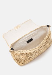 Bolso de paja tejido en color natural con un interior de tela marrón claro, que cuenta con un solo bolsillo y un cierre de metal dorado.