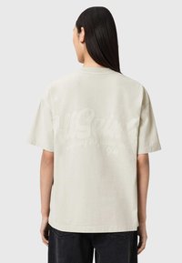 Ανοιχτό γκρι βαμβακερό T-shirt με άνετη εφαρμογή, κοντά μανίκια και μεγάλο, μονοχρωματικό γραφικό λογότυπο και κείμενο τυπωμένα στην πλάτη.