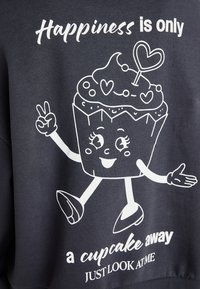 Tmavý mikina s bielou grafikou, ktorá zobrazuje veselú postavičku cupcake, s textom "Šťastie je len na dosah cupcakes" a hravými detailmi.