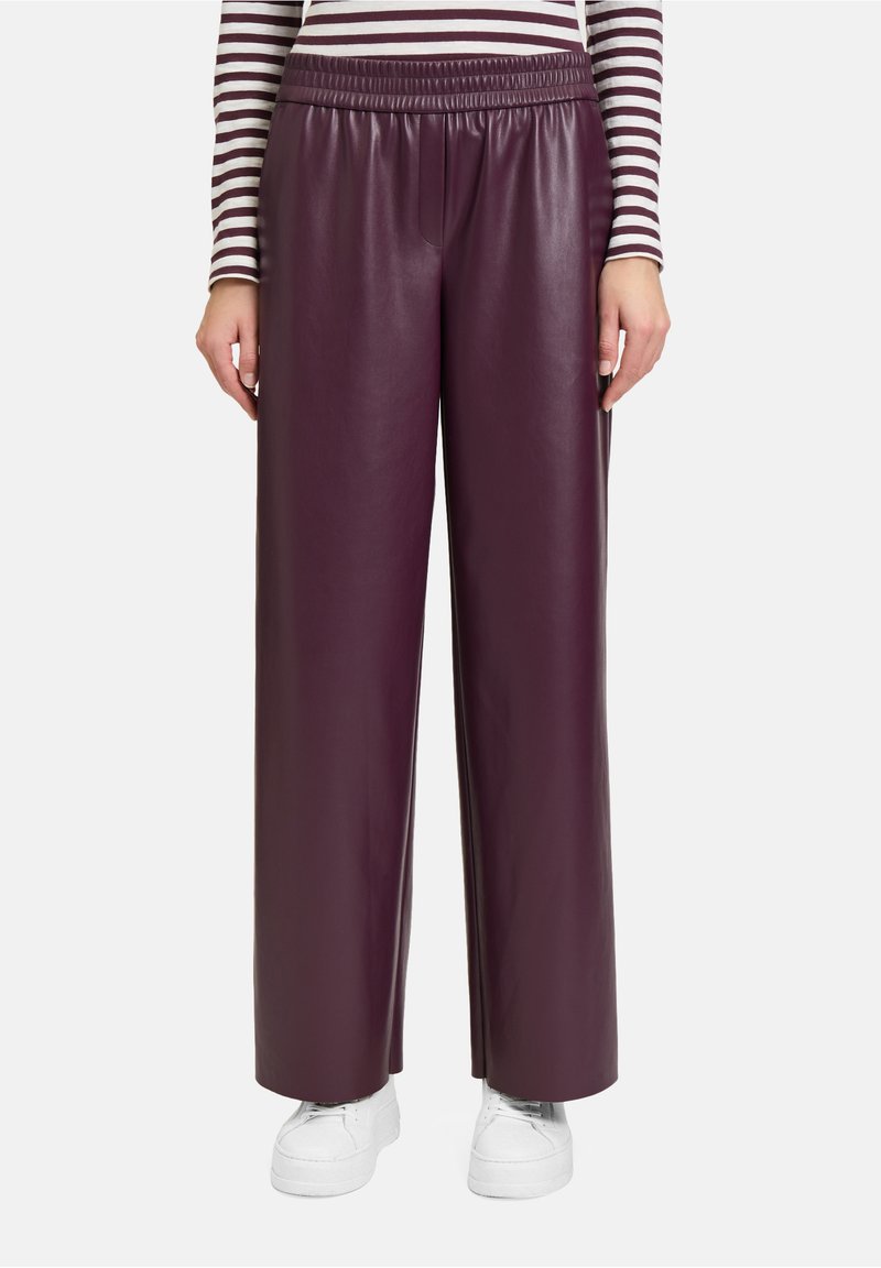 Bordeaux neplederen broek met wijde pijpen, een elastische tailleband, een gladde textuur en gecombineerd met witte sneakers.