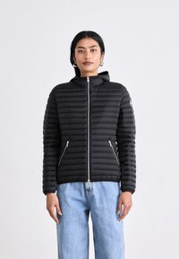 Melnā pūkaina jakā ar pieguļošu dizainu, horizontālu quilted rakstu, ar rāvējslēdzēju un divām sānu kabatām. Tam ir arī kapuce un logo akcents.