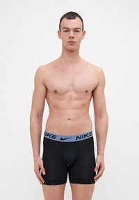 Nike črne bokserice imajo tesen kroj, elastičen pas z modrim logotipom in gladek, raztegljiv material za udobje.