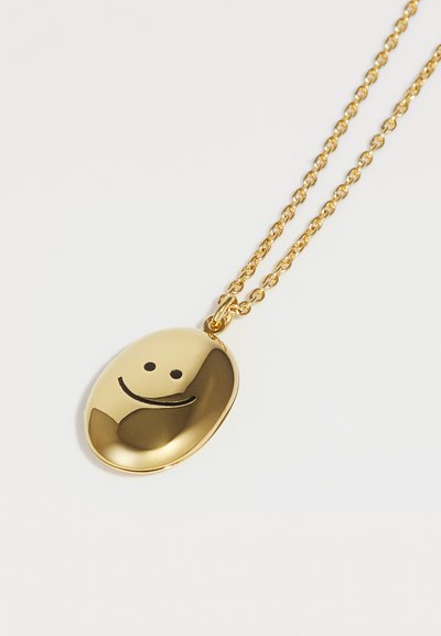 Guld vedhængs halskæde med en oval form, der har en glat overflade og et enkelt smiley ansigt design. Kædelinks er runde og polerede.