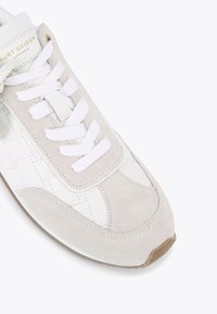 Sneaker che presenta un mix di pelle bianca e suede grigio chiaro, lacci bianchi piatti, linguetta imbottita e una suola in gomma texturizzata.