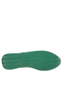 Semelle en caoutchouc verte avec un motif en chevrons distinctif, tige blanche et design minimaliste.