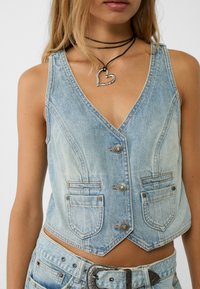 Jasnoniebieska kamizelka denimowa z dekoltem w serek, dwiema przednimi kieszeniami oraz skróconym fasonem, z metalowymi guzikami i kontrastowymi przeszyciami.