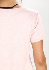Camiseta de manga corta rosa con un corte holgado. Tejido suave y ligero con cuello redondo y un sutil detalle de tiras negras en la parte posterior.