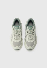Ténis de desporto verde claro com materiais em malha e sintéticos, apresentando atacadores, colarinho acolchoado e logótipo da Asics na lingueta.