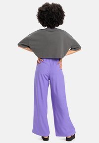 Cropped gray t-shirt with short sleeves, paired with loose-fitting, high-waisted purple pants. Smooth fabric and elastic waistband.
