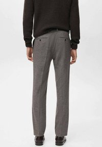Pantaloni grigi a quadrettini con taglio dritto, dotati di tasche posteriori e design frontale piatto. Abbinati a un maglione a coste scuro.