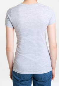 Camiseta corta de manga gris, textura suave, diseño ajustado, cuello redondo, vista desde atrás, combinada con pantalones vaqueros azules holgados.
