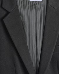 Blazer nero con tessuto testurizzato, rever a punta e foderatura interna a strisce grigie. Include tasche laterali e vestibilità sartoriale.