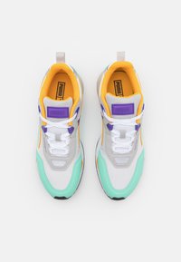 Sneakers con una toma in rete bianca, decorata con accenti grigi, verde menta e arancione, accompagnati da un colletto imbottito giallo e un marchio viola.
