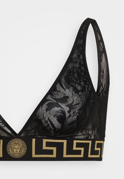 Melnas mežģīņu bralette, kas izceļ ziedu rakstus, dziļu izgriezumu un plašu melnu joslu ar zelta grieķu atslēgas dizainu un Medūzas logotipu.