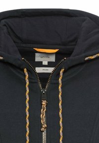 Marinblaues Organic-Hoodie mit durchgehendem Reißverschluss, akzentuiert mit strukturierten gelben und grauen Kordeln und einem Etikett mit der Bezeichnung "L".