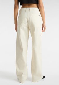 Crème-kleurige wijde broek met een hoge taille, voorzien van twee achterzakken en een soepele katoenstof. Aangekleed met een detail van een zijzak.
