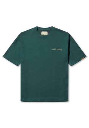 Green cotton T-shirt with short sleeves, crew neck, and gold "PAS DE MONACO" text on the front. Smooth texture, standard fit.