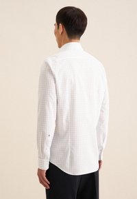 Camicia bianca a maniche lunghe con motivo a quadri blu, polsino abbottonato e colletto classico. Tessuto di cotone morbido con orlo dritto sul retro.