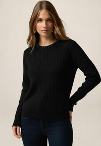 Pulover negru din tricot răsucit cu guler rotund și detaliu cu mărgele la guler, având mâneci lungi și siluetă strâmtă.