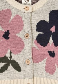 Neulecardigan, jossa on suuria vaaleanpunaisia ja tummansinisiä kukkakuoseja off-white-taustalla. Takissa on puunappia ja ribbireuna.