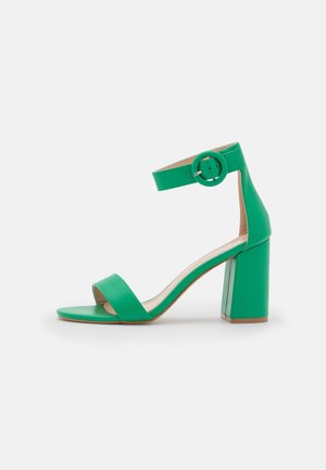 Grøn faux læder sandaler med høje hæle, to brede stropper, ankelrem med en rund spænde og firkantet blokhælf.