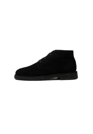 Botas de tobillo de ante negro con punta redondeada, suela de goma plana y diseño de cordones con tres ojales. Textura suave con un minimalismo en los detalles.