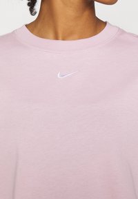 Rosa Nike sweatshirt, rund halsringning, mjukt material, med en liten vit Nike-logga på bröstet. Enkelt mönster, utan mönster eller detaljer.