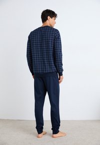 Ensemble de vêtements de détente bleu marine comprenant un haut à manches longues à carreaux et un pantalon fuselé assorti, avec des poignets côtelés et une coupe décontractée.