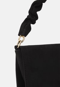 Czarna zamszowa torebka z wiązanym paskiem z materiału, z metalową klamrą w złotym kolorze. Gładka faktura i precyzyjne przeszycia wzdłuż krawędzi.