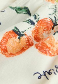 Tissu blanc avec des fruits orange imprimés et des feuilles vertes dans un style texturé et pictural, accompagné de texte cursif partiel en bleu foncé.