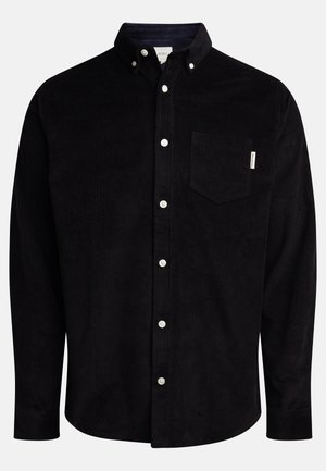 Camisa de pana negra con cuello abotonado, bolsillo frontal y botones blancos; presenta rayas verticales texturizadas y mangas largas.