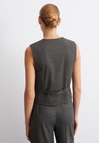 Gray pinstripe vest with a sleeveless design and a double-button accent at the back. Tailored fit with a smooth texture.