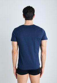 Camiseta de algodón azul marino con cuello redondo y mangas cortas, con un diseño liso y textura suave, vista desde la parte posterior.