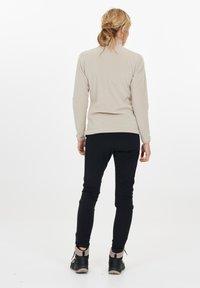Lysbeige langærmet top med en blød tekstur, parret med sorte afslappede bukser og sorte sko. Sættet har et enkelt design.
