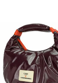 Lila glänzende Handtasche mit abgerundeter Form, ausgestattet mit orangefarbenen Metallakzenten und einem Markenetikett an der Seite. Strukturierte Oberflächendetails.