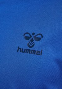 Blått tyg med en svart stiliserad bi-logotyp och ordet "hummel" tryckt på det.