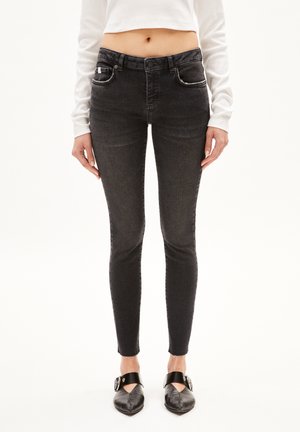 Schwarze Skinny-Jeans in einer verwaschenen Optik, mit vorderen Taschen und einem klassischen Knopfverschluss. Der Stoff hat eine glatte, leicht dehnbare Textur.