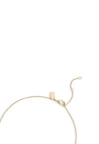 Bracelet ton or avec un design délicat en chaîne, doté d'une fermeture à mousqueton et d'une petite étiquette rectangulaire près du fermoir.