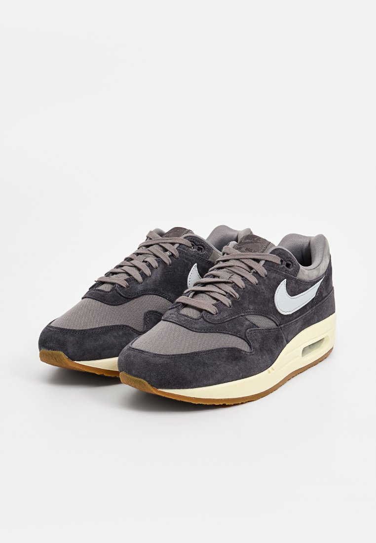 Nike sneakers met een grijs suède en mesh bovenwerk, met een lichtgrijze swoosh, een kenmerkende luchtvering eenheid en een gumrubberen buitenzool.