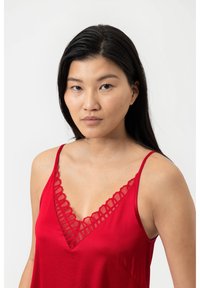 Camisola rossa con bordo in pizzo lungo il collo a V, realizzata in tessuto morbido. Presenta spalline sottili e una vestibilità rilassata.