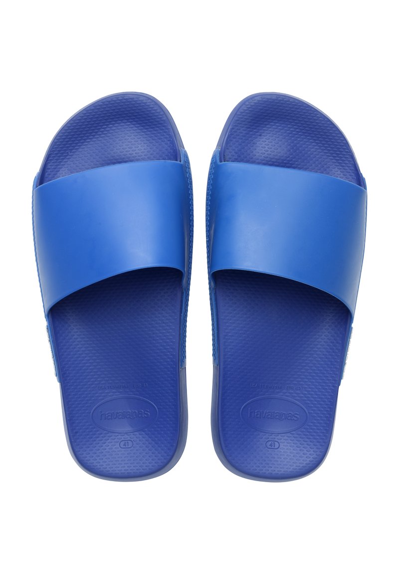 Zilas plastmasas čības ar plašu siksnu un teksturētu zolīti. Zoles ir gludas, un dizainā ir redzams logo sānos.