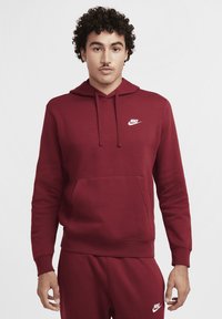 Nike hoodie in bordeaux materiaal met een voorzak, capuchon met trekkoord en wit logo op de borst; heeft lange mouwen en een ontspannen pasvorm.