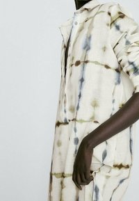 Pitkä, napillinen paita kevyestä kankaasta, jossa on vaalean kerman värinen pohja ja sitruunaväriä vihreissä ja sinisissä väreissä. Pehmeä rakenne.